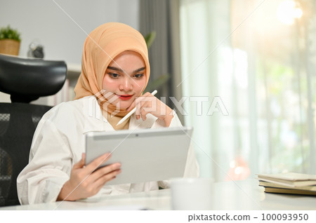 Professional Asian Muslim businesswoman using her digital tablet, focusing on her marketing project. Professional Asian Muslim businesswoman using her digital tablet, focusing on her marketing project. 100093950