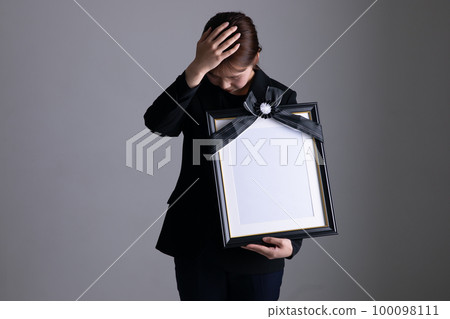 A woman crying with a portrait of the deceased portrait of the deceased A woman crying with a portrait of the deceased portrait of the deceased 100098111