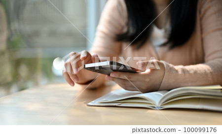 Young Asian female using his phone while relaxing in the library or coffee shop. cropped image Young Asian female using his phone while relaxing in the library or coffee shop. cropped image 100099176