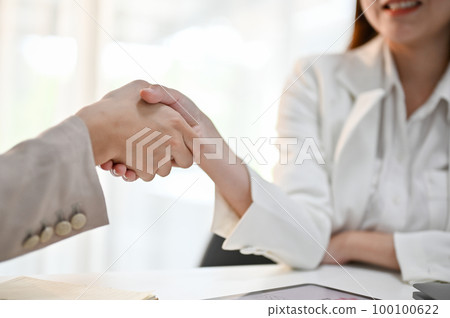 Close-up image of millennial Asian two office employees shaking hands in the meeting. Close-up image of millennial Asian two office employees shaking hands in the meeting. 100100622