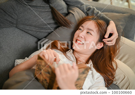 Happy Asian female lesbian couple spending quality time at home, enjoy reading a book together Happy Asian female lesbian couple spending quality time at home, enjoy reading a book together 100100660