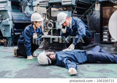 An employee making an emergency call at a factory 100100715