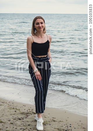Young woman standing on blurred beachside background. Attractive female enjoying walking the sea shore. travel and active lifestyle concept. Springtime. Relaxation, youth, love, lifestyle solitude Young woman standing on blurred beachside background. Attractive female enjoying walking the sea shore. travel and active lifestyle concept. Springtime. Relaxation, youth, love, lifestyle solitude 100103833