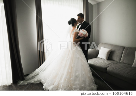 Beautiful bride and groom embracing and kissing on their wedding day Beautiful bride and groom embracing and kissing on their wedding day 100104615
