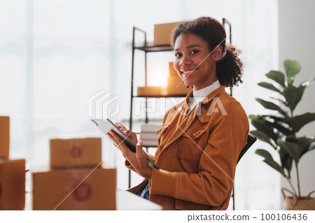 American African entrepreneur smile and use a tablet to check online order. Successful SME entrepreneur concept 100106436