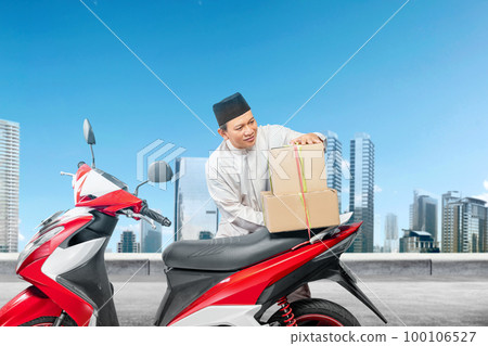 Asian Muslim man tying box on motorcycle prepare for mudik 100106527