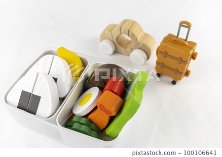 A toy car, a carry bag, and a lunch box. Image of eating lunch on a trip 100106641