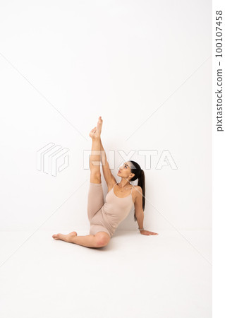 Girl doing stretching in the studio on a white background. A beautiful gymnast with a flexible body and athletic uniform Girl doing stretching in the studio on a white background. A beautiful gymnast with a flexible body and athletic uniform 100107458