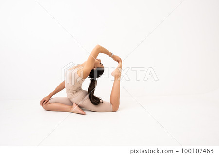 Girl doing stretching in the studio on a white background. A beautiful gymnast with a flexible body and athletic uniform Girl doing stretching in the studio on a white background. A beautiful gymnast with a flexible body and athletic uniform 100107463