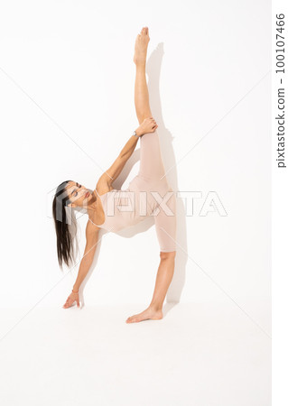 Girl doing stretching in the studio on a white background. A beautiful gymnast with a flexible body and athletic uniform 100107466