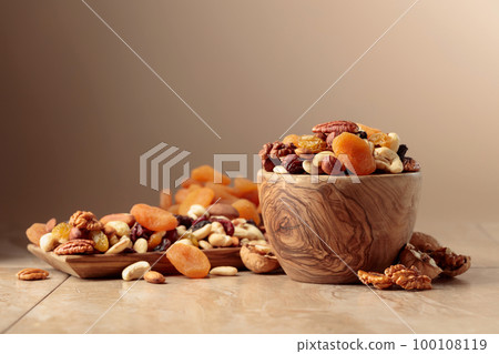 Dried fruits and nuts on a beige ceramic table. 100108119