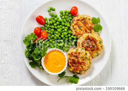 crab cakes with sauce, green peas, tomatoes 100109666
