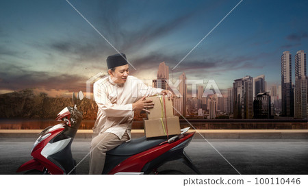 Asian Muslim man tying box on motorcycle prepare for mudik 100110446