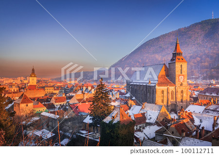 Brasov, Romania. Winter snowy downtown, sunset time, Black Church and Carpathian Mountains 100112711
