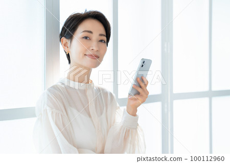 使用智能手機的中年時尚女性 100112960