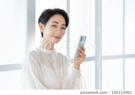 使用智能手機的中年時尚女性 100112962