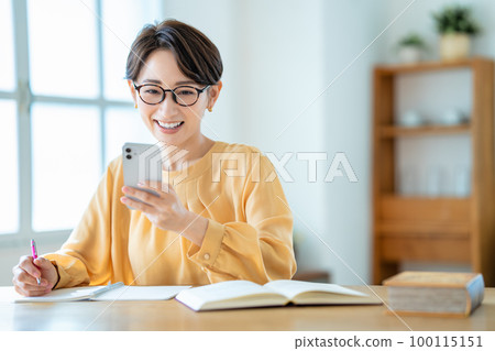 Middle-aged woman studying with a smartphone Middle-aged woman studying with a smartphone 100115151