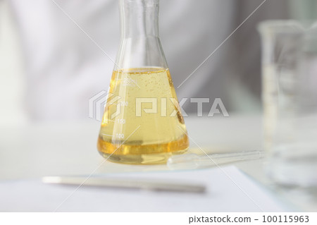 Close-up of flask with yellow liquid on table of research laboratory. 100115963