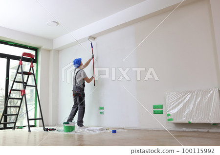 Male painter paints house wall with roller brush. Male painter paints house wall with roller brush. 100115992