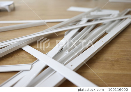 Many white plastic cable trays on wooden floor close up. 100116000