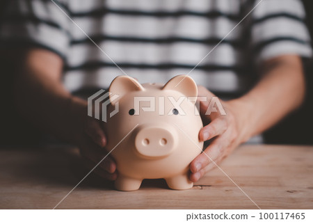 Man hand holding piggy bank on wood table. Saving money wealth and financial concept. Business, finance, investment, Financial planning. Man hand holding piggy bank on wood table. Saving money wealth and financial concept. Business, finance, investment, Financial planning. 100117465