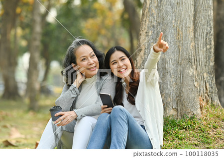 Beautiful middle age mother and adult daughter relaxing in the park. Mother's day, family, relationships and love concept Beautiful middle age mother and adult daughter relaxing in the park. Mother's day, family, relationships and love concept 100118035