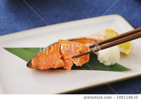 Grilled salmon fish lifted with chopsticks 100118610