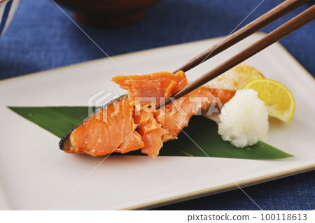 Grilled salmon fish lifted with chopsticks 100118613