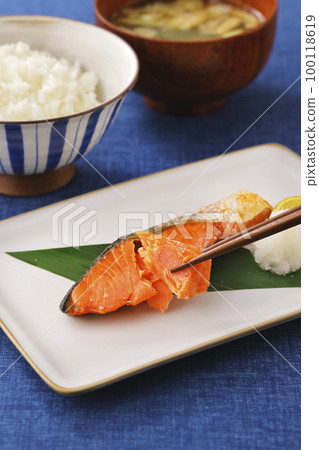 Grilled salmon fish lifted with chopsticks 100118619