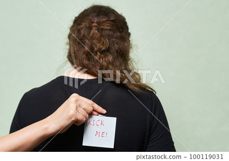 Cropped shot of woman putting note with april fools day lettering on back of another woman, april fools day concept Cropped shot of woman putting note with april fools day lettering on back of another woman, april fools day concept 100119031