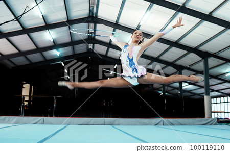 Gymnastics, woman athlete and performance at gym, fitness and leap, legs stretching and in the air with flexibility. Exercise, competition and professional female gymnast with sports and hula hoop Gymnastics, woman athlete and performance at gym, fitness and leap, legs stretching and in the air with flexibility. Exercise, competition and professional female gymnast with sports and hula hoop 100119110