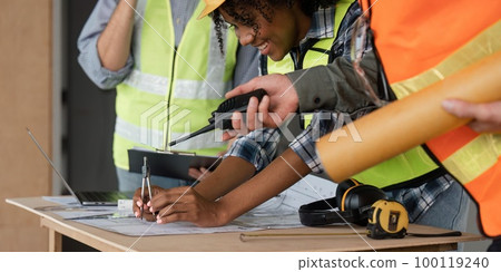 Architect team working with blueprints for architectural plan, engineer sketching a construction project on table in working site Architect team working with blueprints for architectural plan, engineer sketching a construction project on table in working site 100119240