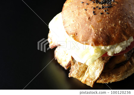 BLT 漢堡的鳥瞰圖，上面有培根、生菜和番茄，上面有塔塔醬，黑色背景突出 100120236