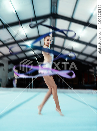 Portrait, ribbon and motion blur with a woman gymnast in a studio for olympics dance training or exercise. Fitness, art and gymnastics with a female dancer in a gymnasium for rhythmic practice 100120553