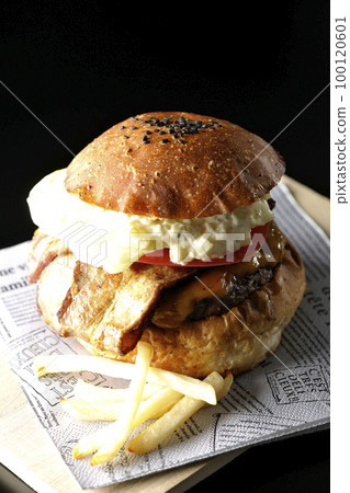 BLT burger and fries with bacon, lettuce and tomato with tartar sauce protruding in black background 100120601