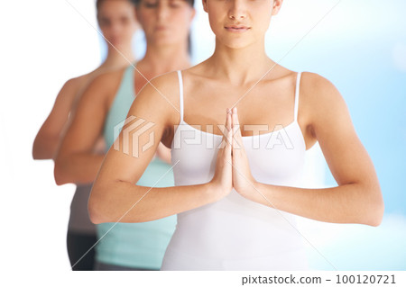 Seeking calm and serenity. Group of serene yoga practitioners meditating together - cropped. 100120721