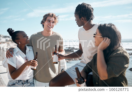 Couple of friends, talking or drinking beer by beach, ocean or sea in holiday vacation, summer travel or social gathering. Smile, happy or bonding people and alcohol drinks for diversity celebration 100120771