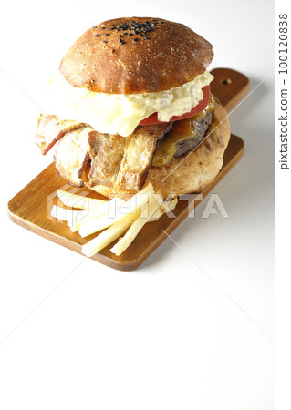 BLT burger with tartar sauce protruding and bacon, lettuce and tomato sandwiched between potatoes and a white background 100120838
