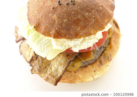 A BLT burger with tartar sauce protruding and bacon, lettuce and tomato sandwiched in a white background 100120996