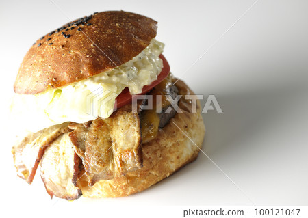 A BLT burger with tartar sauce protruding and bacon, lettuce and tomato sandwiched in a white background A BLT burger with tartar sauce protruding and bacon, lettuce and tomato sandwiched in a white background 100121047