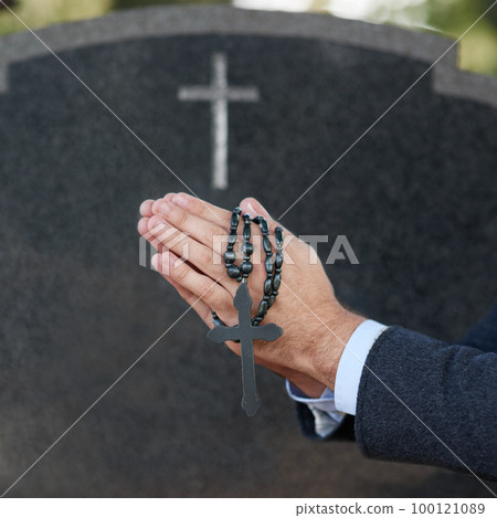 Praying for eternal peace. Cropped shot of a man praying with a rosary at a gravesite. Praying for eternal peace. Cropped shot of a man praying with a rosary at a gravesite. 100121089