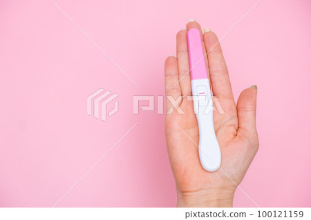 Female hand holding a positive pregnancy test on the pink background. Planning of pregnancy and motherhood concept with copy space Female hand holding a positive pregnancy test on the pink background. Planning of pregnancy and motherhood concept with copy space 100121159