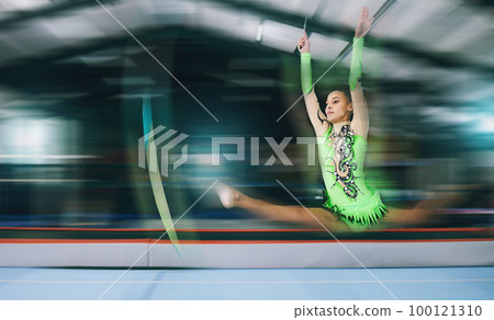 Gymnastics, fitness and woman with jump and motion blur, sport in gym or arena with action and speed. Athlete, moving and mockup space with gymnast, flexibility and pose with sports and splits in air 100121310