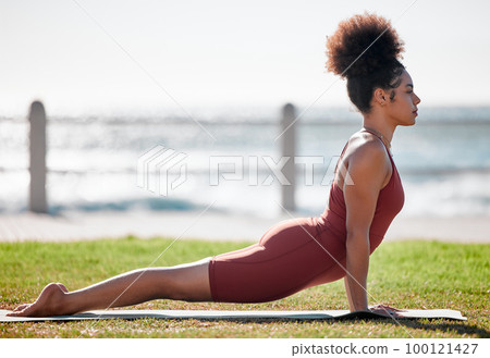 Yoga, fitness and black woman stretching on grass for healthy lifestyle, body wellness and cardio workout. Sports, pilates training and girl doing meditation, cobra stretch and exercise for peace 100121427