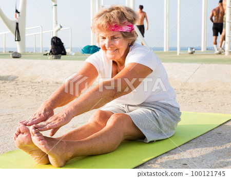 Old lady sitting on mat outdoors Old lady sitting on mat outdoors 100121745