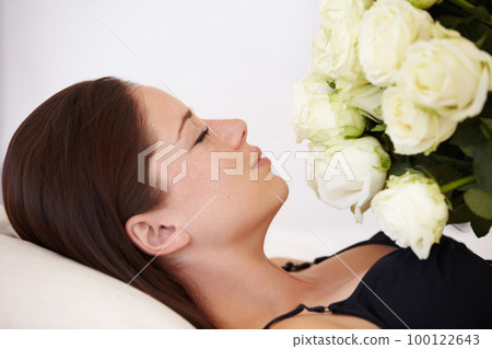 Flowers, roses and woman sleeping in bedroom for resting, relax and peaceful with eyes closed. Flower bouquet, love and girl smell blossom of valentines day gift, present and romantic gesture in bed 100122643