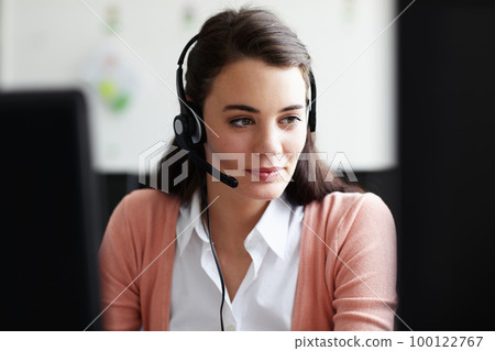 Conscientious young worker. A pretty young woman wearing a headset looking at her computer screen. 100122767