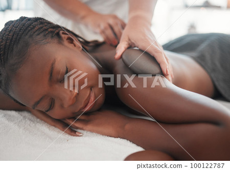 Black woman gets hot stone massage, spa and hands of masseuse, holistic and wellness physical therapy. Health, peace with face and self care with zen, stress relief for people and back skin detox Black woman gets hot stone massage, spa and hands of masseuse, holistic and wellness physical therapy. Health, peace with face and self care with zen, stress relief for people and back skin detox 100122787