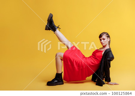 Beautiful female model in a red dress yellow background Beautiful female model in a red dress yellow background 100125864