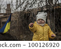 Little girl in front of defensive structures of Ukrainian army. War in Ukraine. Children and war concept. Support for Ukraine. Stop war. Humanitarian disaster concept. Ukrainian flag 100126920